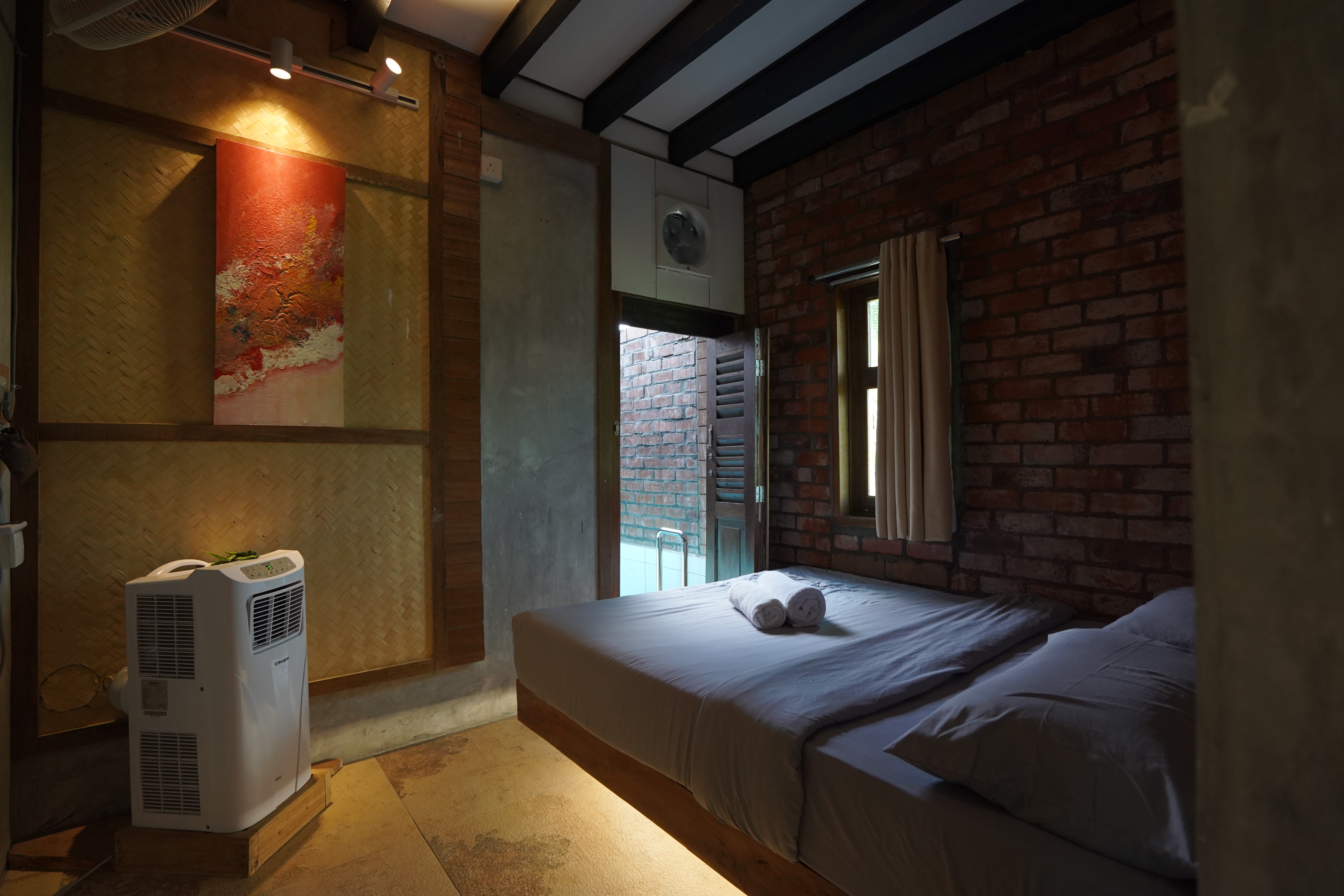 Bedroom with brick, timber and woven bamboo walls at Villa Sawah